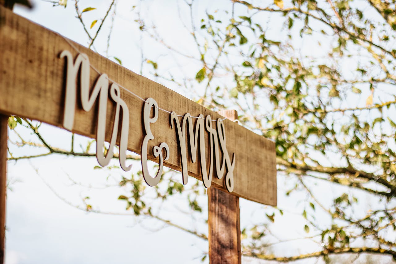 gallery-4 Charming 'Mr & Mrs' sign hanging outdoors on a sunny day, ideal for rustic weddings.