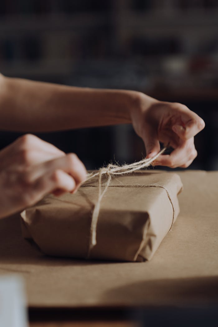 services-02 Hands tying twine around a craft paper wrapped gift, symbolizing care and personal touch.